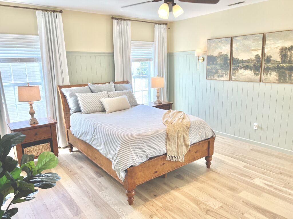 French Cottage Bed angled with pictures on wall, sconces and fiddle fig tree