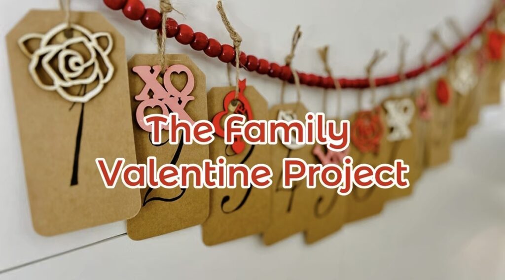 Craft Tags with numbers and wooden valentine tags hanging on red beads on shiplap wall with label "The Family Valentine Project"